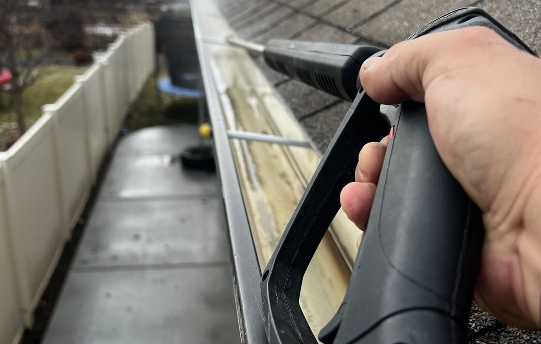Flushing debris from a home eavestrough along the roofline